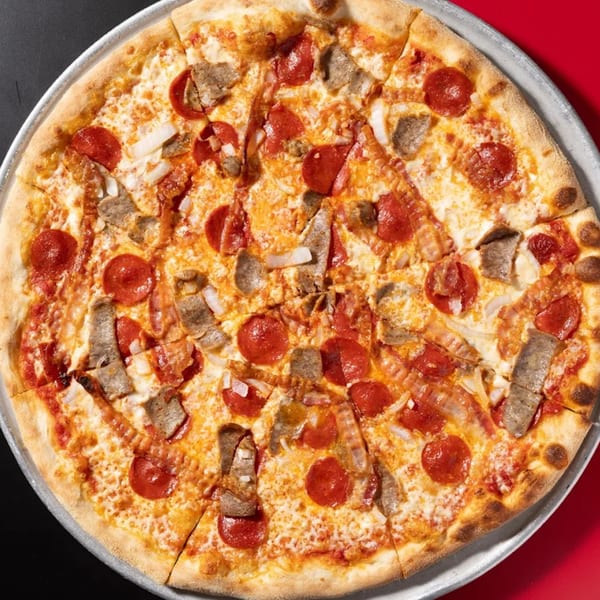 Halftime Pizza's pepperoni, sausage, bacon, and onion pizza on a metal pan.